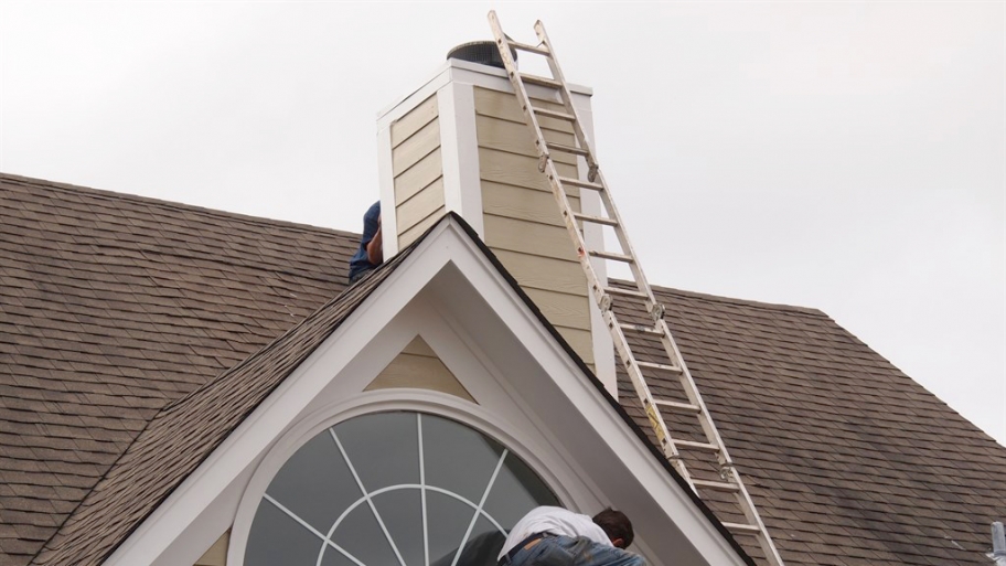 roofer making repairs around window and chimney